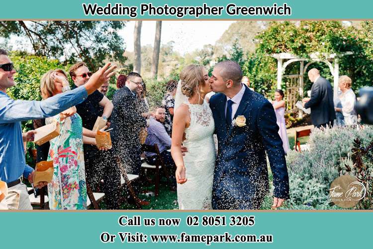 Photo of the Bride and the Groom kissing while showering rice by the visitors Greenwich NSW 2065